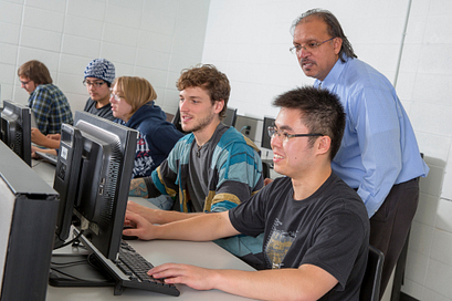 Students work in a computer lab with their professor overseeing their work